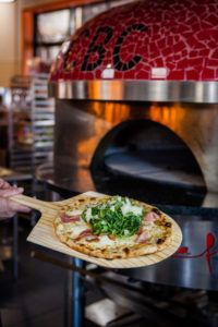 Fresh, Oven Fired Pizza with Pizza Over in the Background